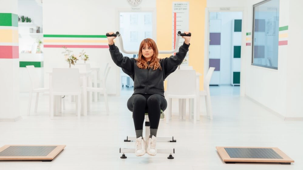 Mujer entrenando en un gimnasio, concentrada en mantener una postura correcta mientras realiza un ejercicio de fuerza