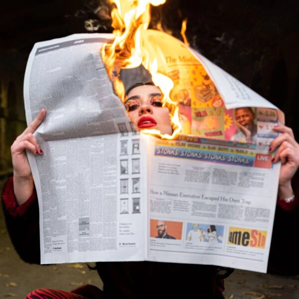 Mujer con expresión de calor y un periódico en llamas alrededor de la cara, representando un sofoco
