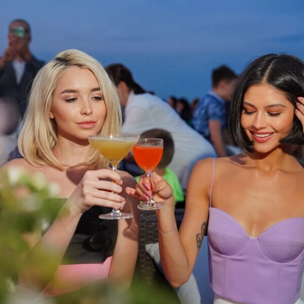 Amigas brindando con bebidas alcohólicas de aspecto refrescante durante el verano, contexto relacionado con el efecto deshidratante del alcohol cuando hace calor